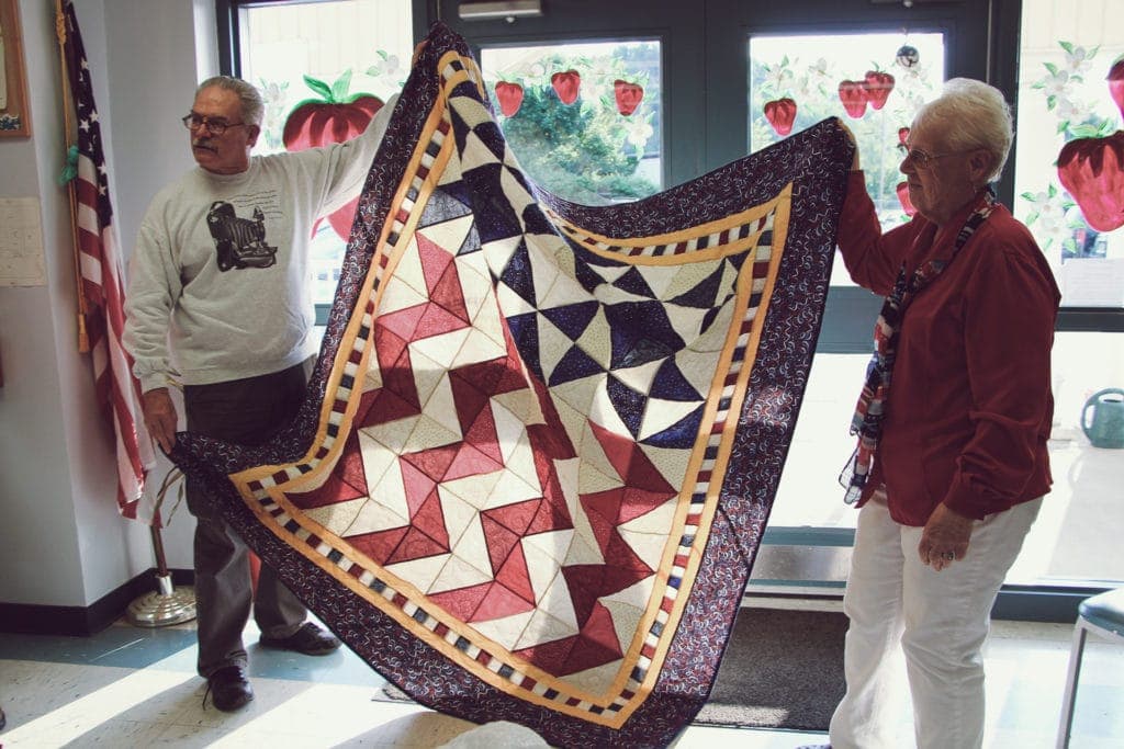 BUCC member Bonne Riffle, right, surprises fellow camera club member John Simons with a Quilt of Valor during the awards ceremony. Simons enlisted in the military service in 1965 and trained at Lackland Airforce Base in Texas. He served three years and nine months.