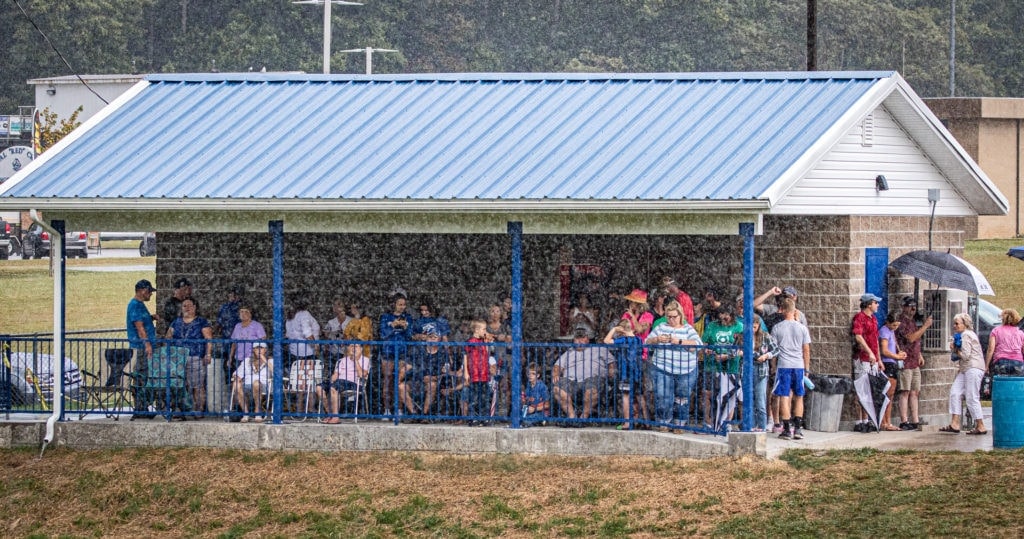 Fans cluster around the concession stand during the downpour at halftime