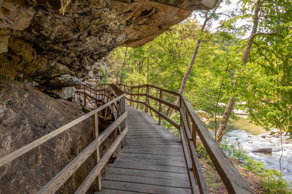 A wooden bridge winds under a rock overhang in Audra State Park.