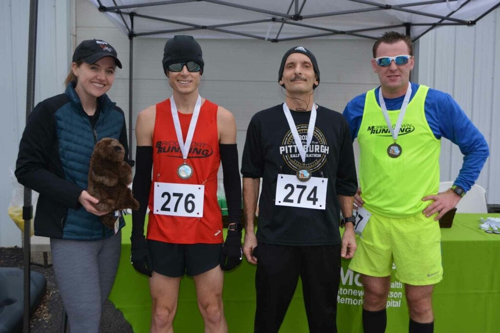 Mon Health Stonewall Jackson Memorial Hospital Physical Therapy intern Katie Ruhstaller awarded the medals during the Fourth Annual Groundhog Day Race in Weston for the top three male racers. Pictured left to right are: Ruhstaller, first place Brian Reider, second place Richard Everly, and third place Keefe Kiser.